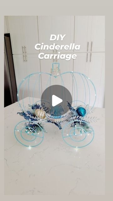 a white table topped with a glass carriage filled with blue flowers and seashells