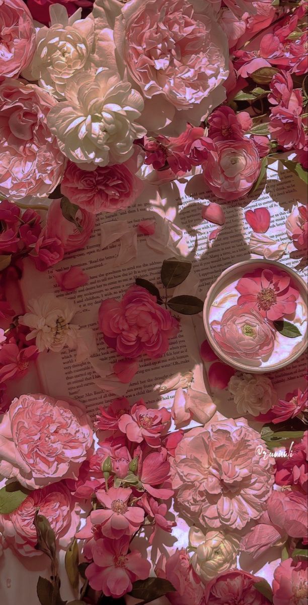 pink and white flowers are on top of an open book