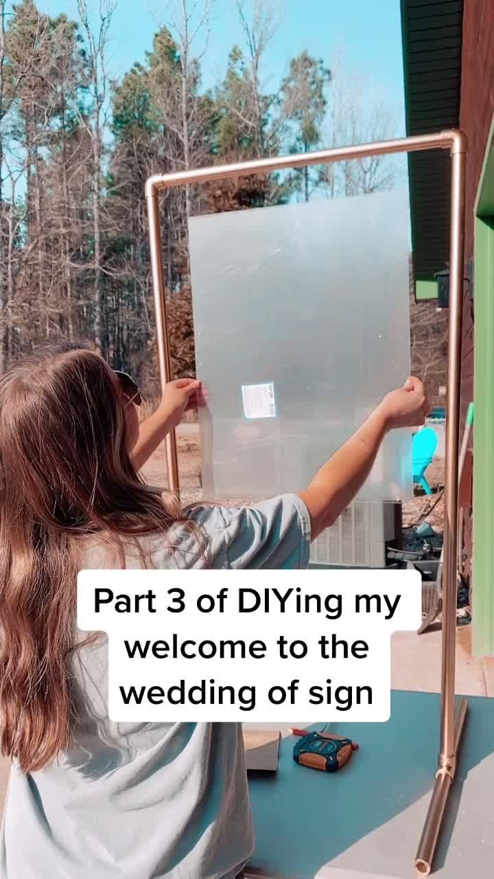 a woman holding up a sign with the words part 2 of dying welcome to wedding of acrylic sign