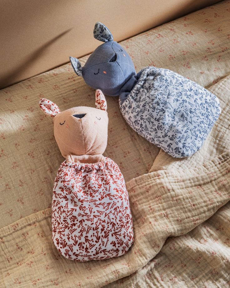 three stuffed animals laying on top of a bed next to each other in different outfits