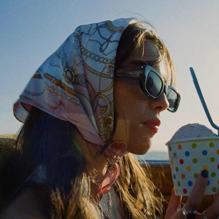 a woman in sunglasses and a bandana eats an ice cream sundae