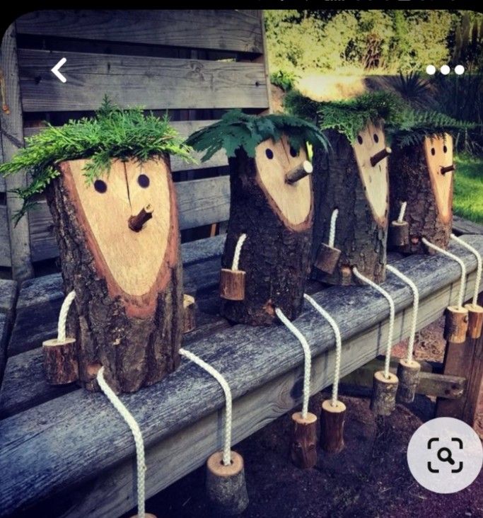 wooden logs with plants growing out of them on a bench in front of some trees