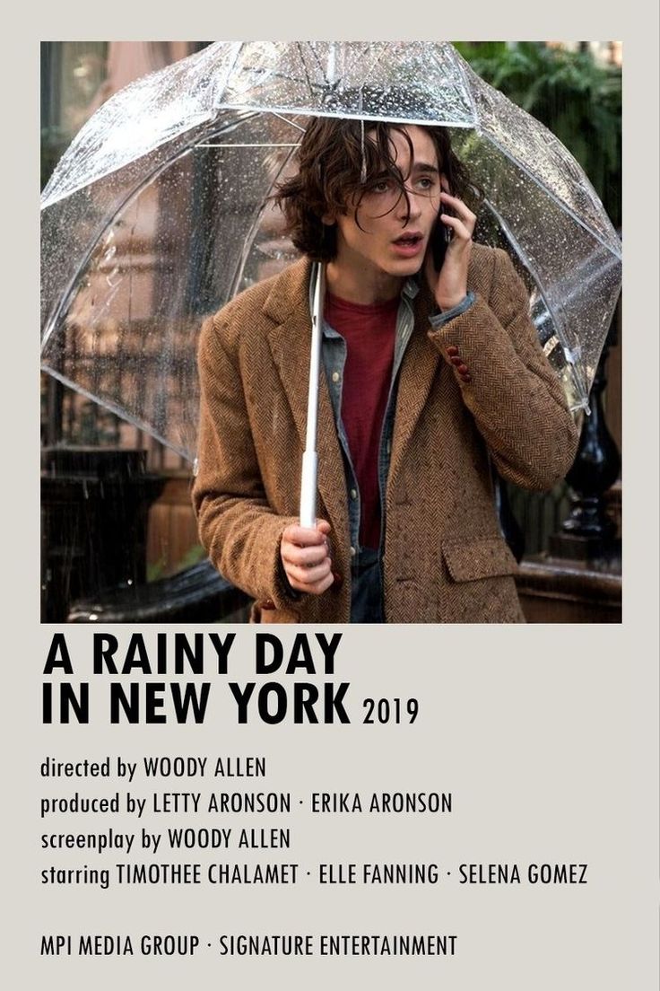 a young man holding an umbrella while talking on the cell phone in front of him