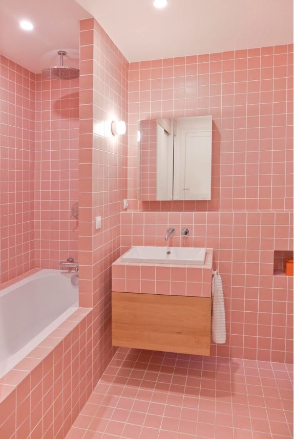 a bathroom with pink tiles on the walls and floor, along with a bathtub