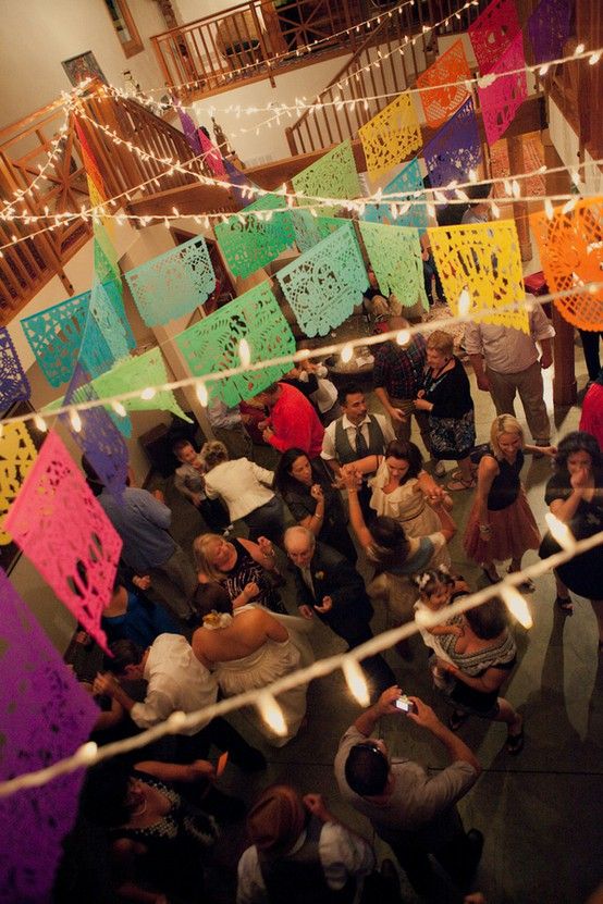 a group of people standing around each other in a room with paper cutouts hanging from the ceiling