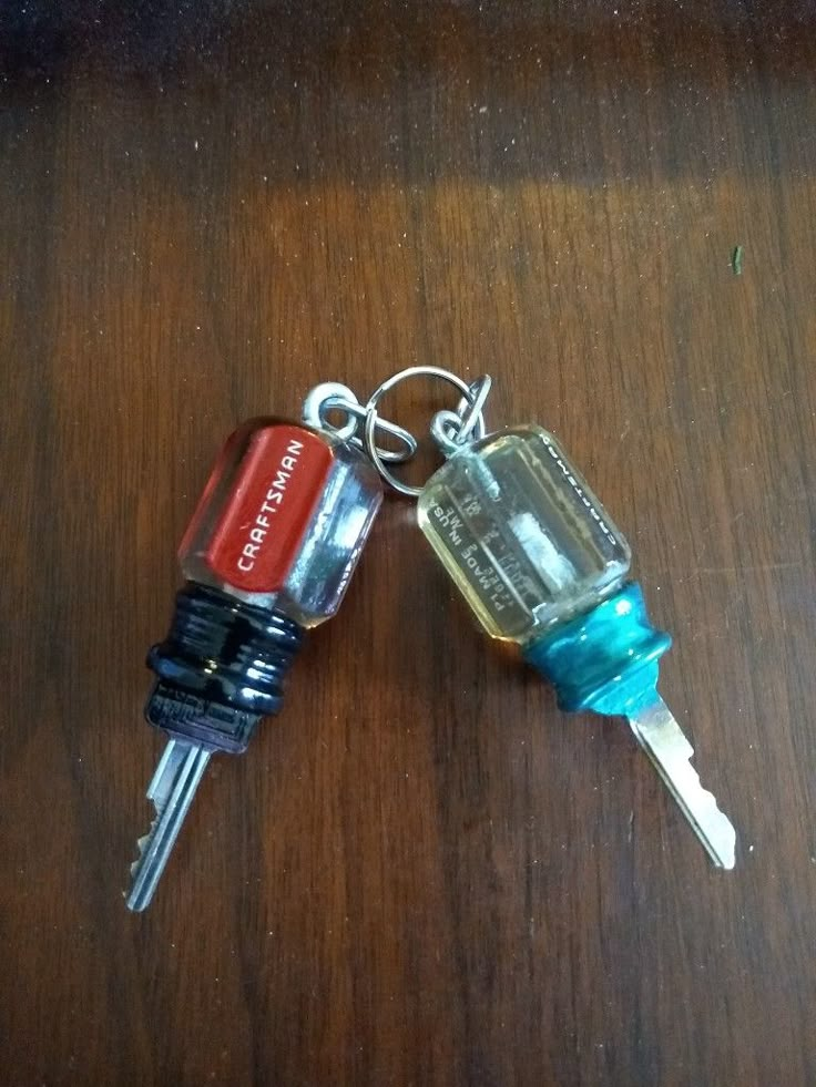 two keys that are sitting on top of a wooden table, one is red and the other is blue