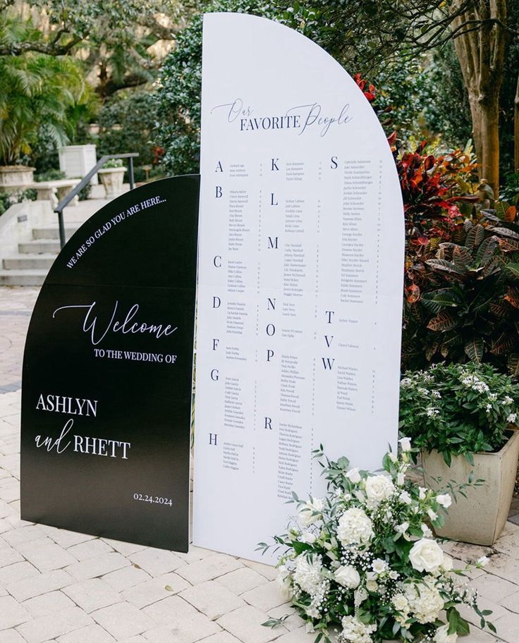 a welcome sign with flowers and greenery next to it