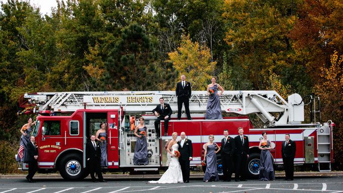 a bride and groom standing on top of a firetruck with their wedding party