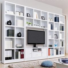 a living room with white bookcases and a flat screen tv on the wall