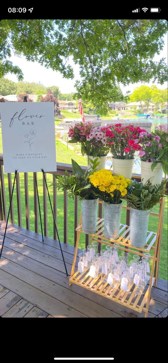 a sign that is on top of a wooden deck with flowers in buckets next to it