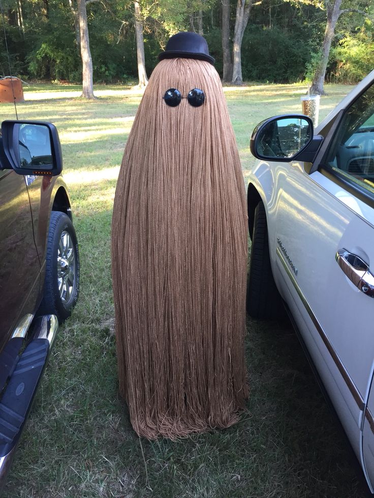 a car parked next to a large long haired wig with eyes on it's head