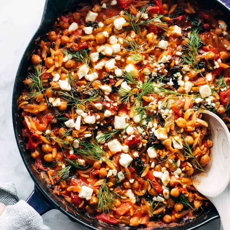 a skillet filled with pasta and garnished with feta cheese on top