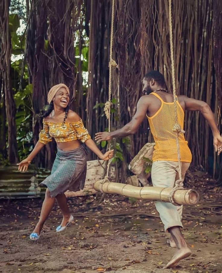 a man and woman playing with a bamboo swing