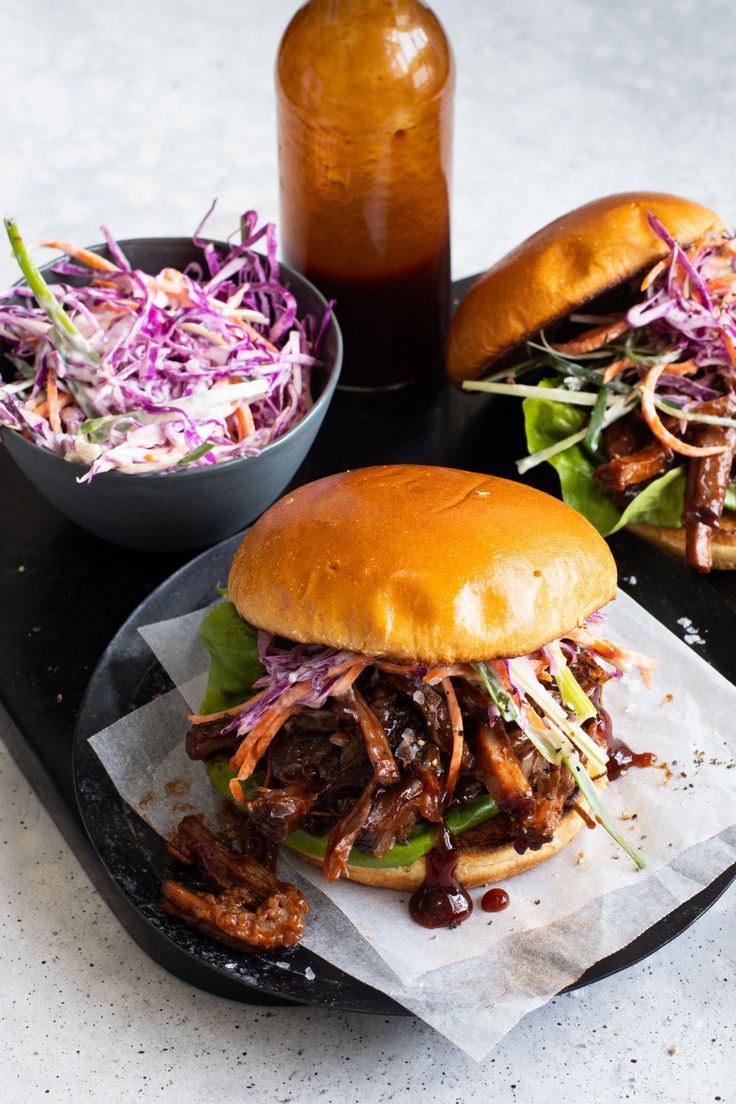 two pulled pork sandwiches with coleslaw slaw and a bottle of bbq sauce