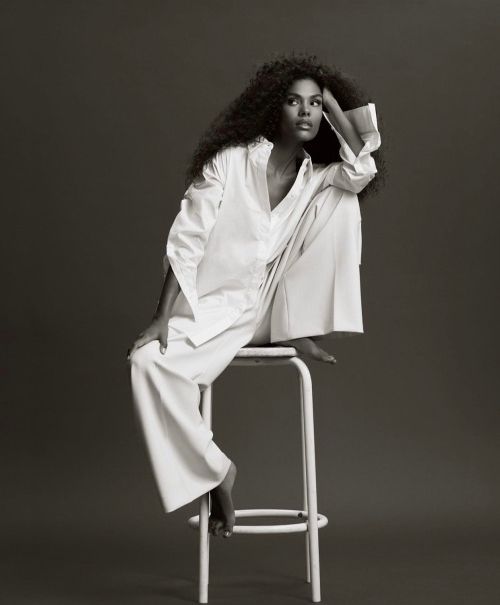 a woman sitting on top of a white chair next to a black and white photo