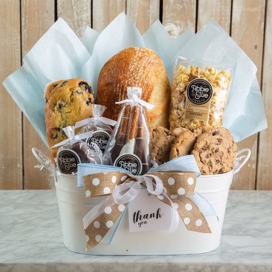 a white bucket filled with cookies, muffins and other treats sitting on top of a table