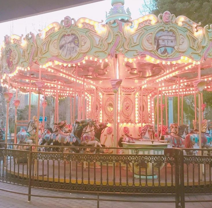 an old fashioned merry go round with lights on it's sides and horses at the top