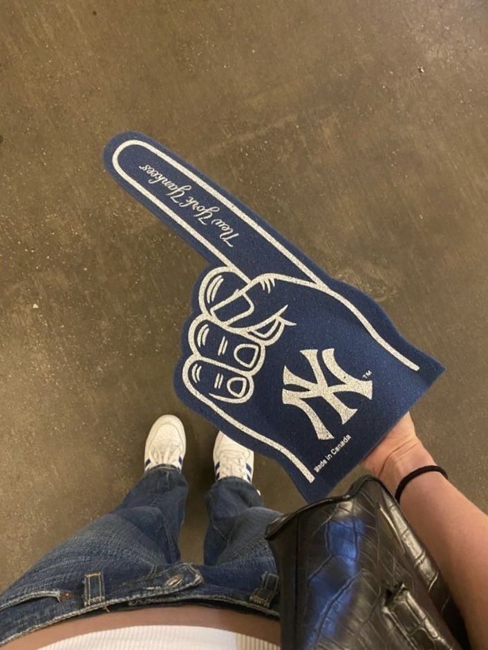 someone is holding up a new york yankees baseball bat shaped pillow on the floor in front of their feet