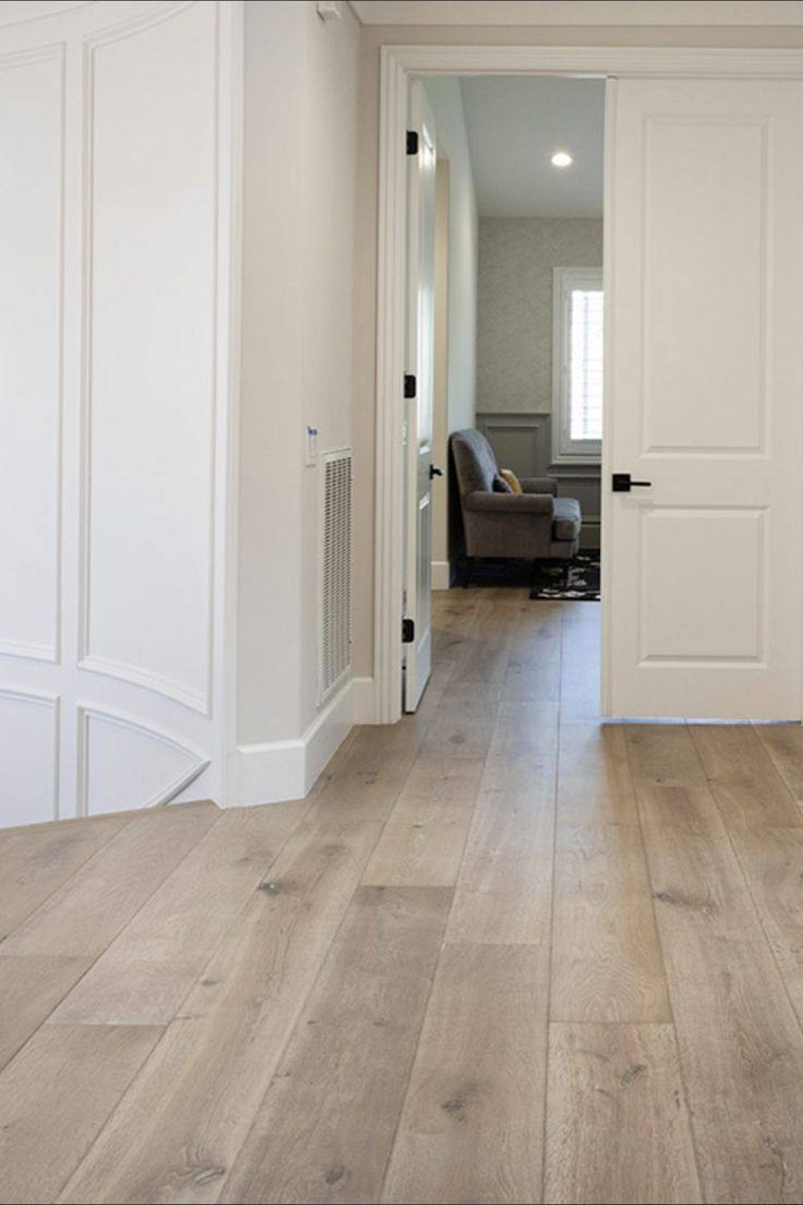 an open door leading to a living room with white walls and wood floors in it