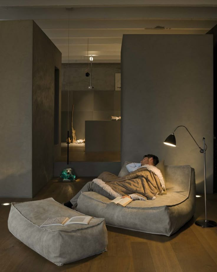 a man laying on top of a couch in a living room next to a lamp