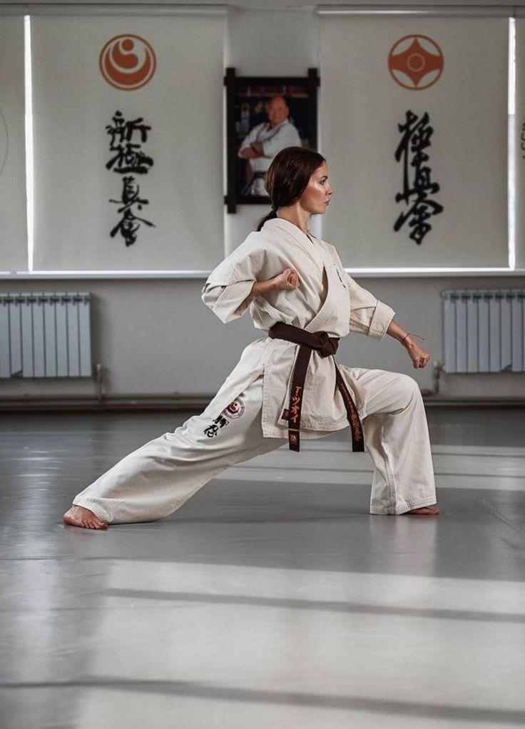 a woman is doing karate in an empty room