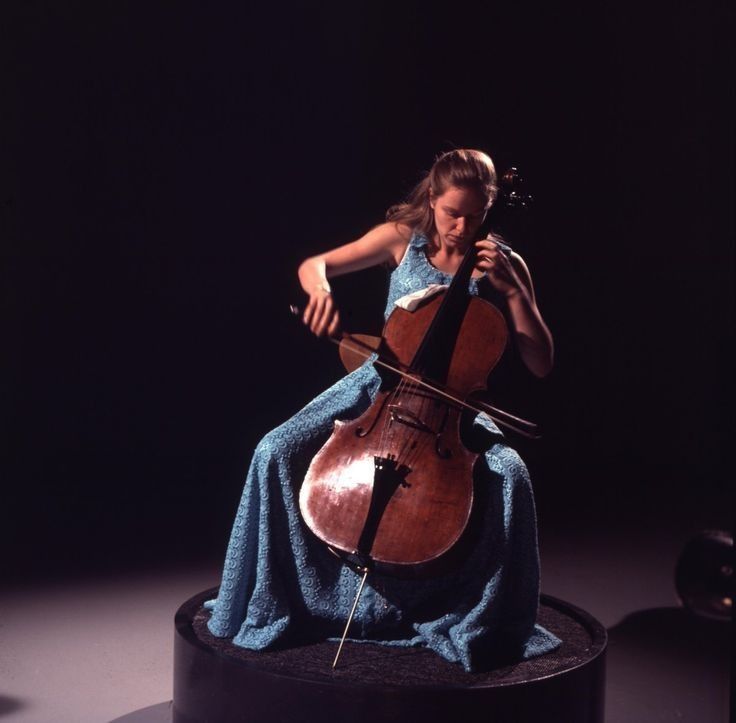 a woman in a blue dress is playing the cello