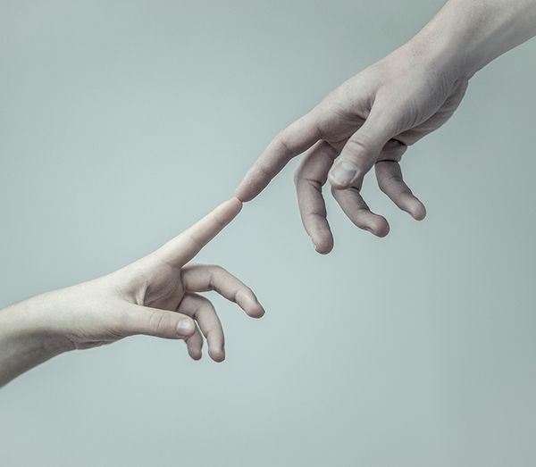 two hands reaching for each other with their fingers extended out to touch the other hand