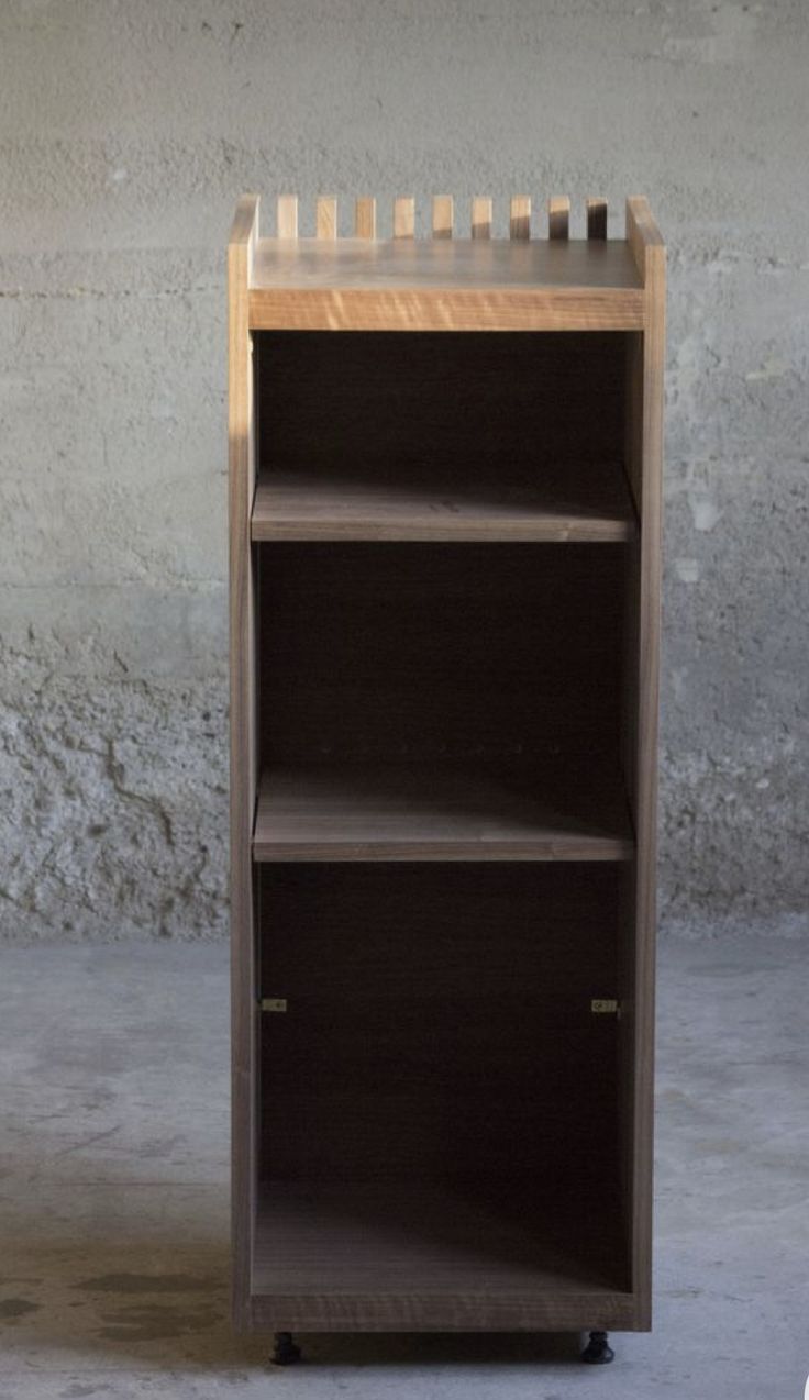 a wooden book shelf sitting on top of a cement floor