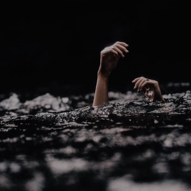 a person is floating in the water with their hands up and one hand extended out