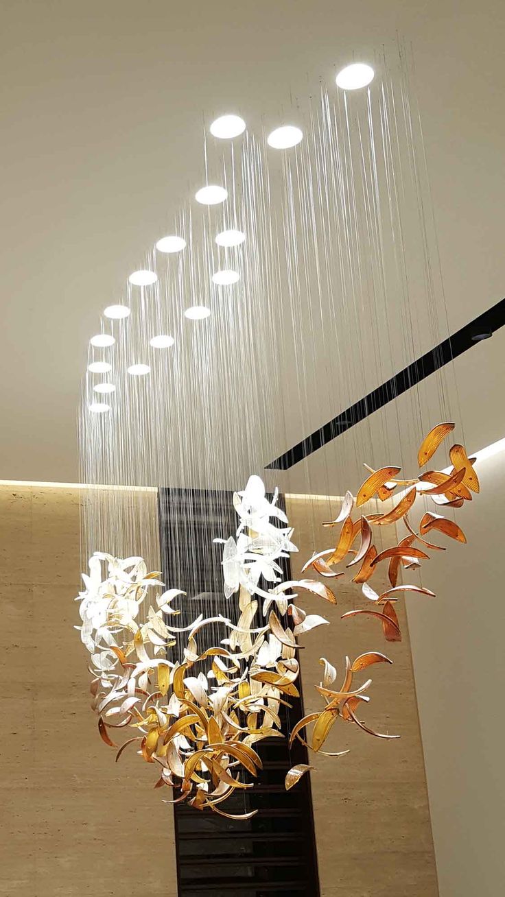 an artistic chandelier hanging from the ceiling in a modern building with white flowers