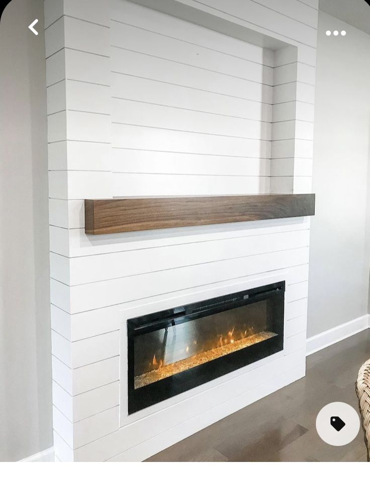 a modern fireplace with white walls and wood trim