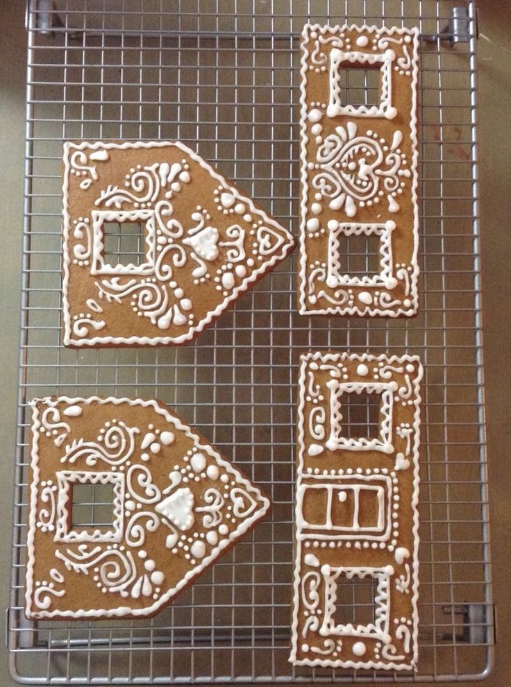 four gingerbread cookies on a cooling rack with icing in the shape of houses