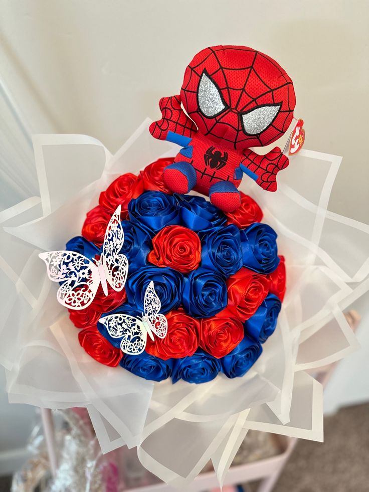 a bouquet of red, white and blue roses with a spiderman decoration on top