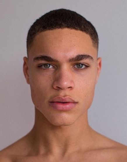 a young man with no shirt on posing for the camera in front of a white wall