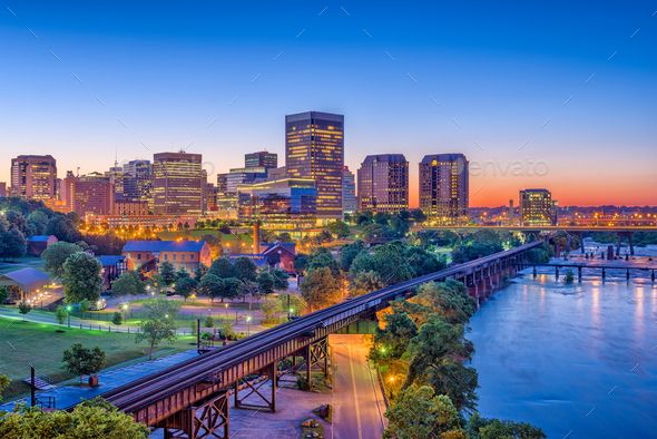 the city skyline at dusk with a bridge and river in foreground