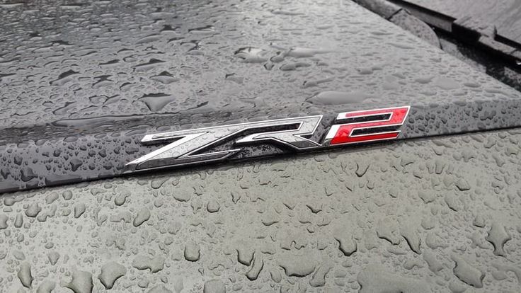 an emblem on the hood of a car covered in rain