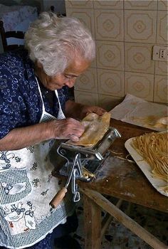 an old woman making pasta in her kitchen