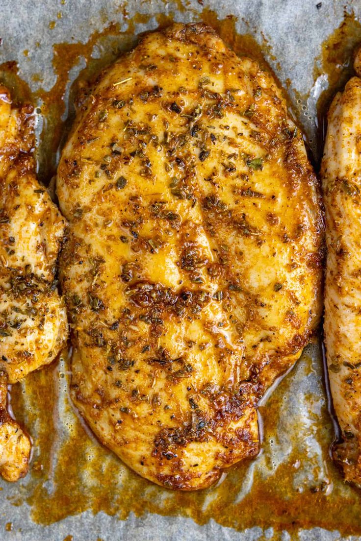 three pieces of chicken sitting on top of a pan covered in gravy and seasoning