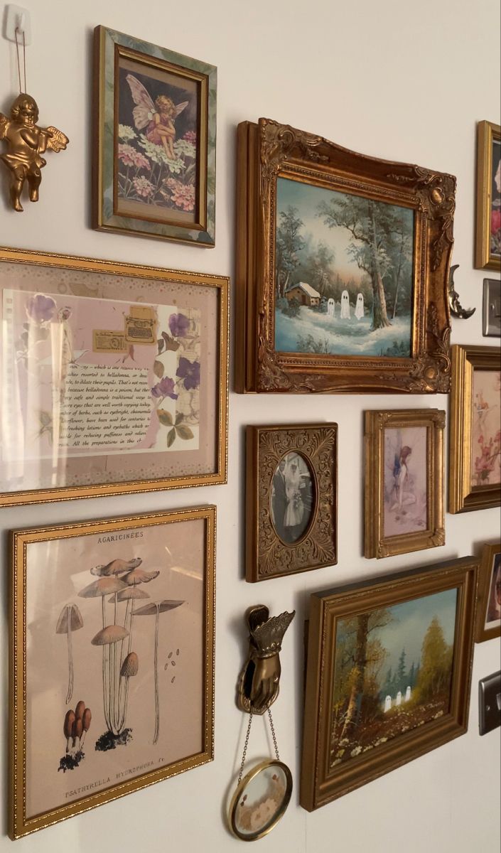 there are many framed pictures on the wall and one has a clock hanging from it