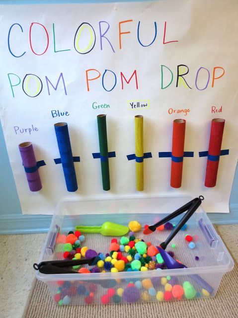 an image of colorful pom poms in a plastic container on the floor next to a bulletin board