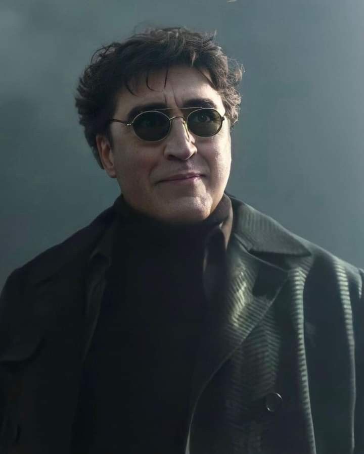 a man wearing sunglasses and a black coat is looking at the camera with an intense look on his face