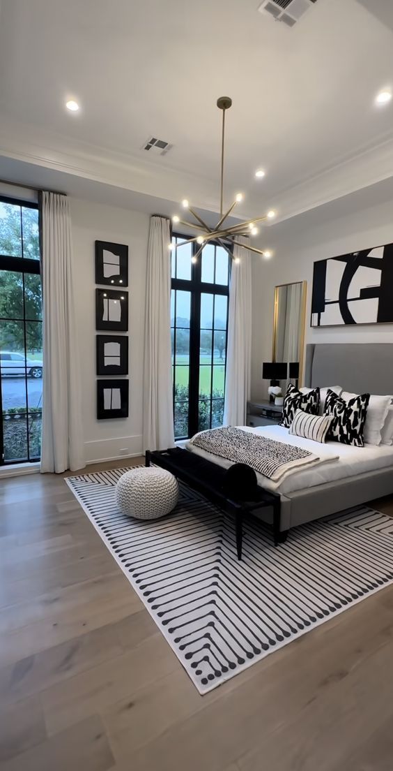 a bedroom with a large bed and lots of windows on the side of the room