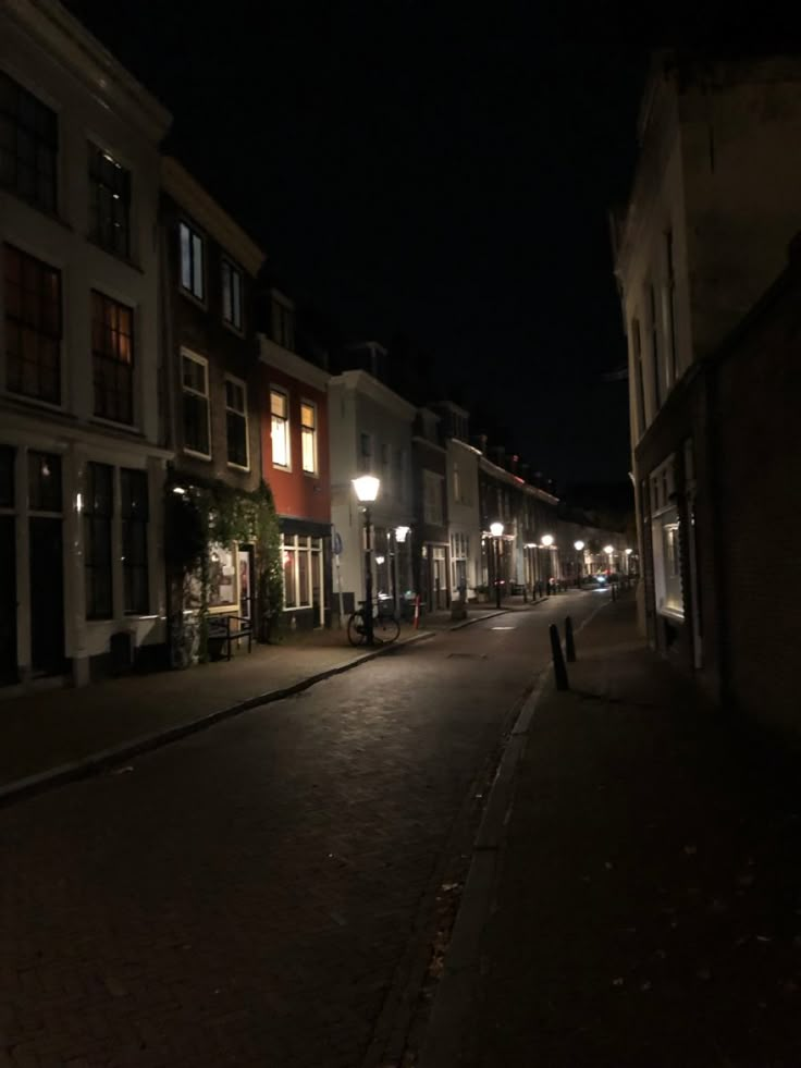 an empty city street at night with no one on the sidewalks or people walking down it