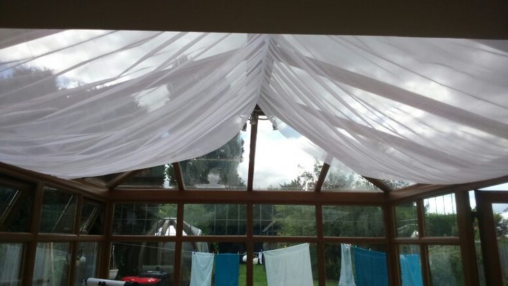 the inside of a house with curtains hanging from it's ceiling and windows open