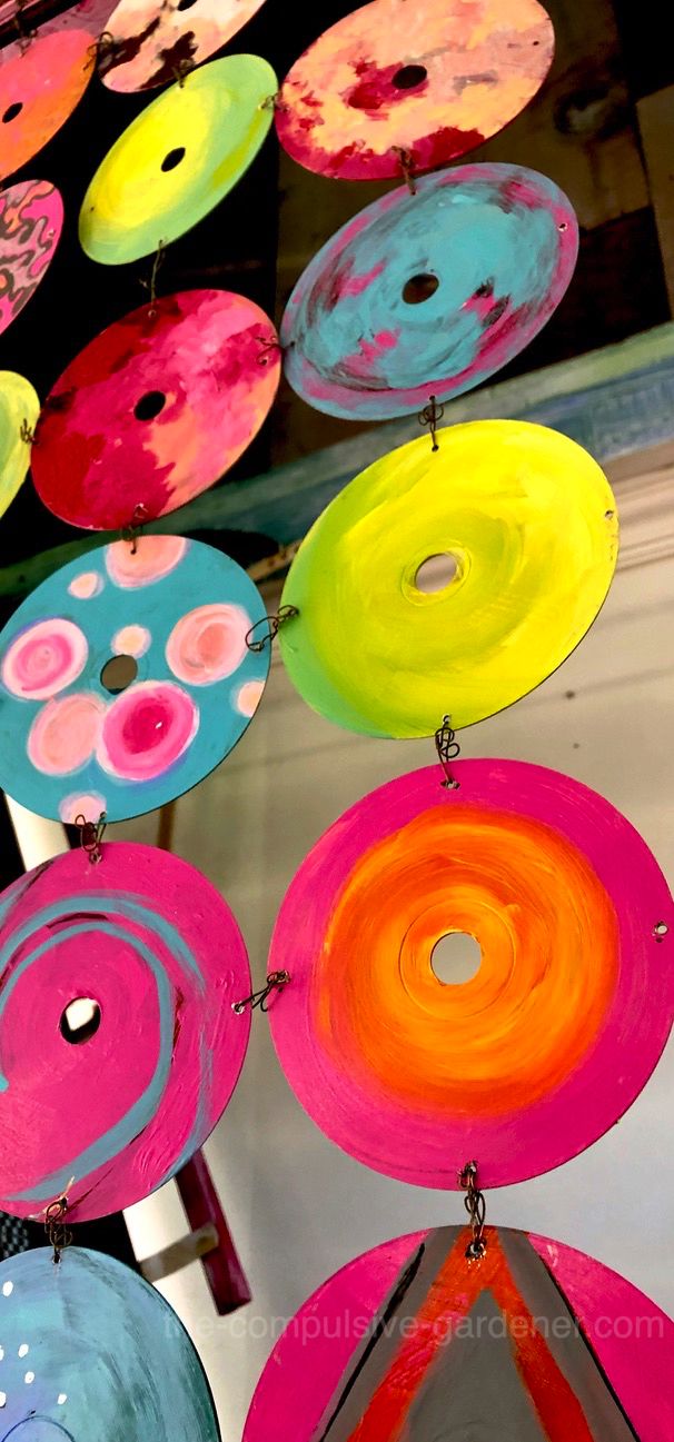 colorful paper plates are hanging from strings in the air, with circles painted on them