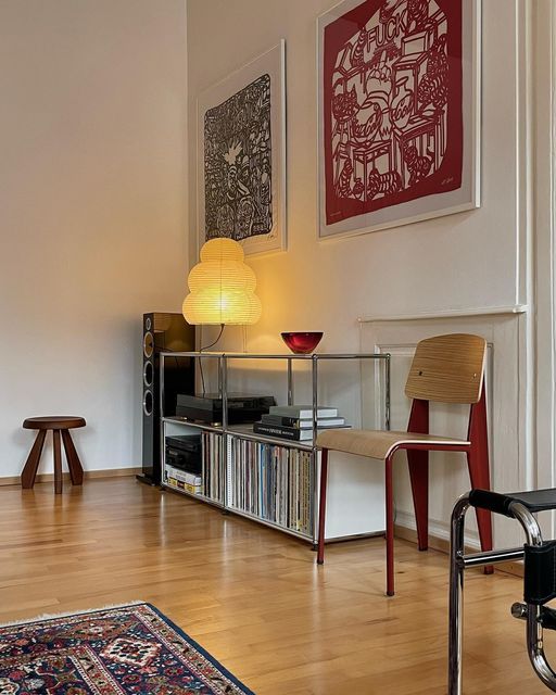 a living room with hard wood floors and white walls, two pictures on the wall