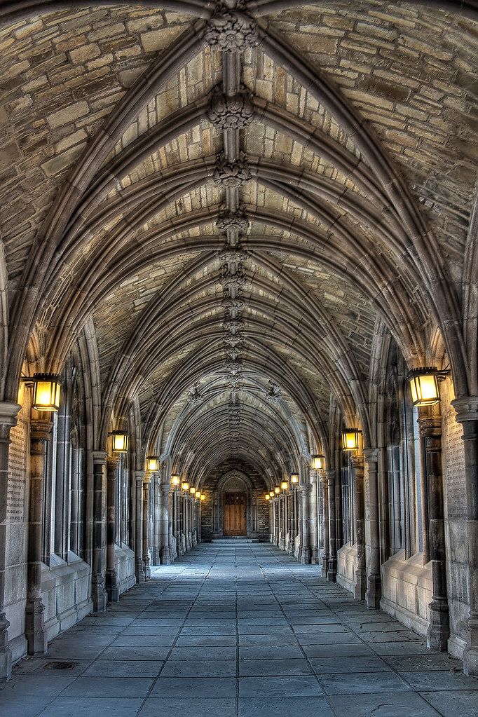 an old looking building with stone arches and lights on either side of the archways