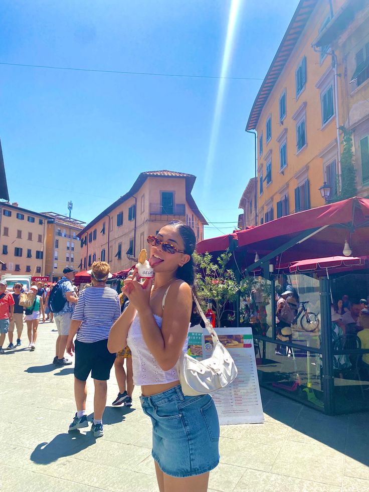 a woman is standing on the street eating an ice cream cone