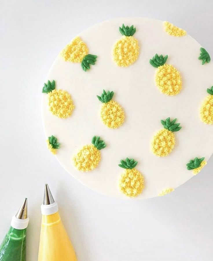 a cake decorated with pineapples on top of a white plate next to yellow crayons