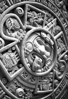 an intricately designed wall in the shape of a circle with faces and symbols on it